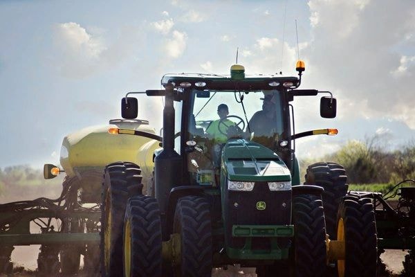 Farmer operating green tractor with sprayer