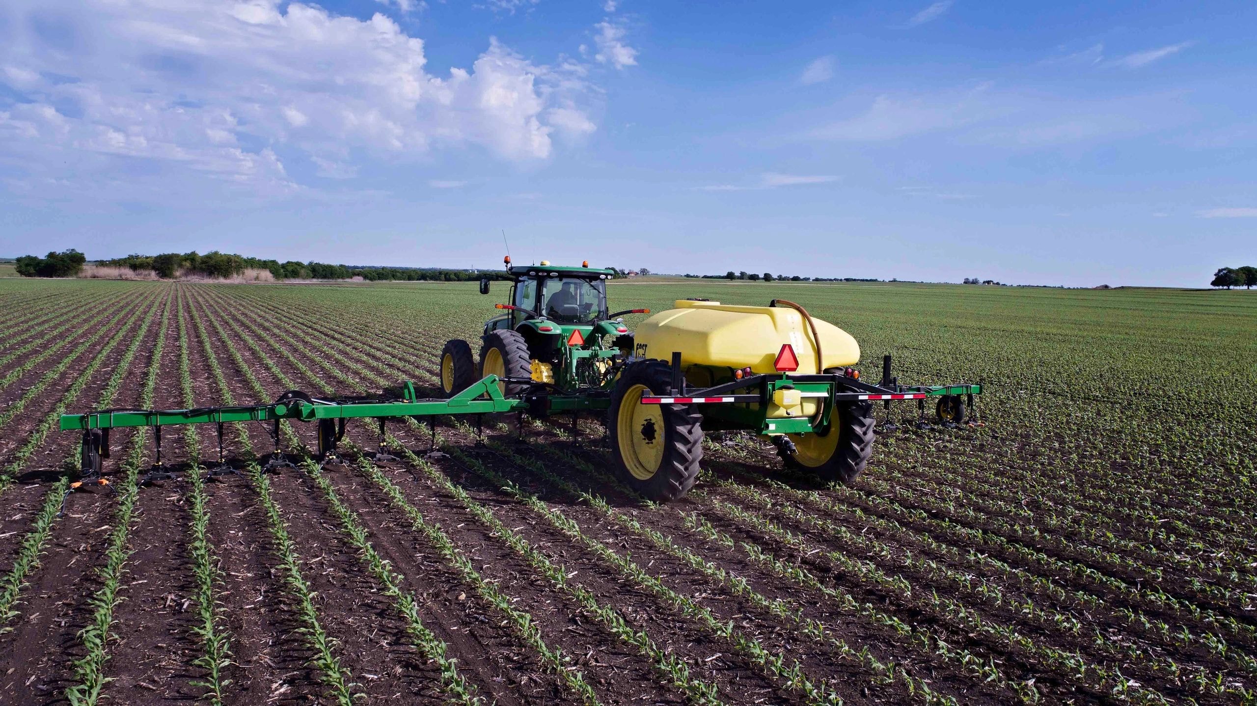 Tractor spraying pesticide corn field